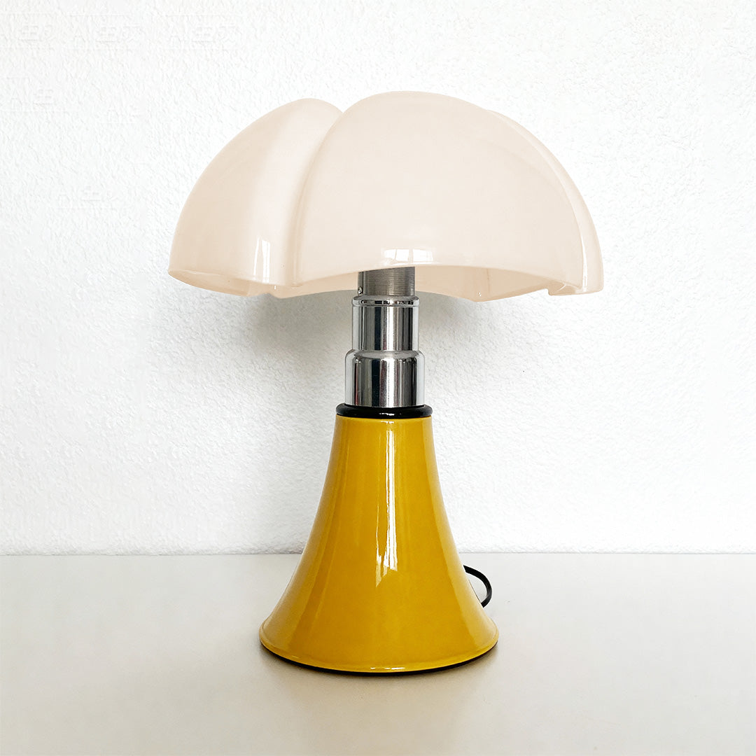 Yellow Bauhaus table lamp with white shade placed on minimalist white desk.