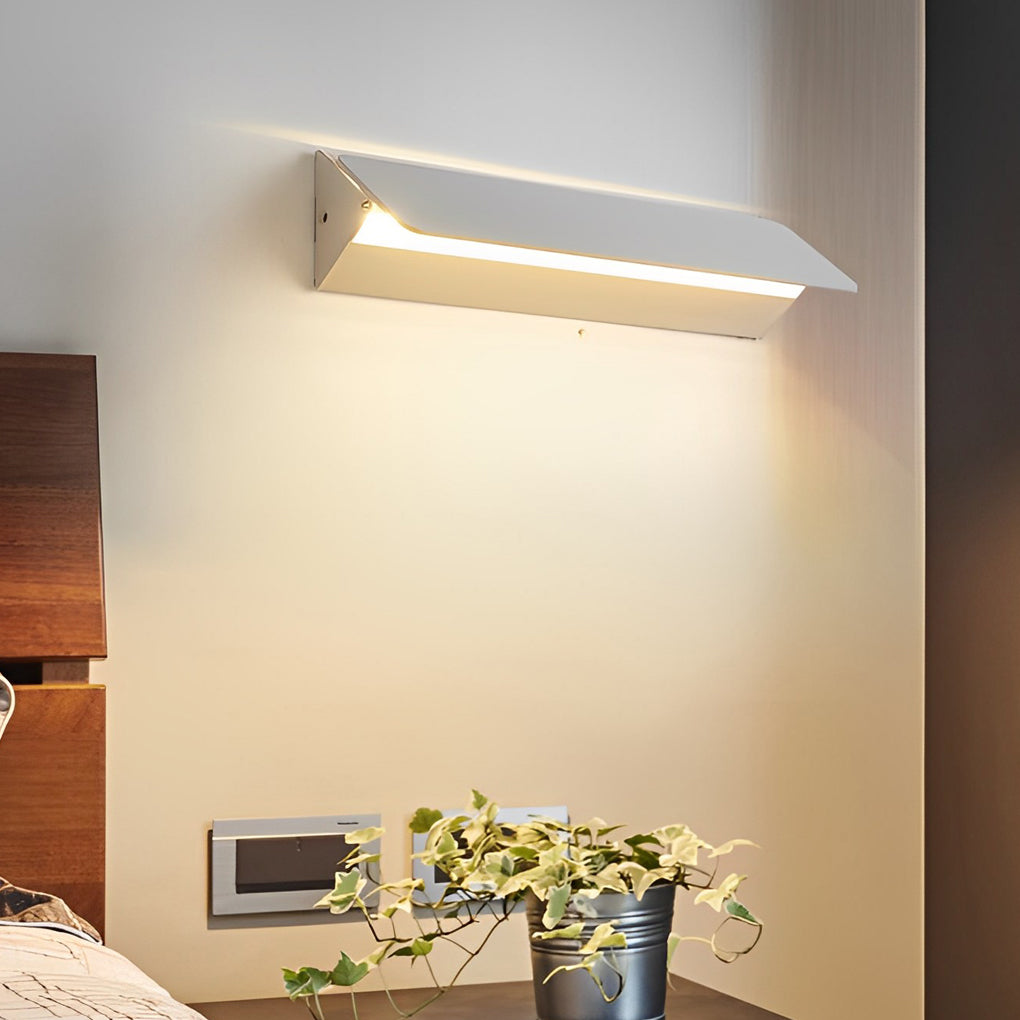 Adjustable wall light angled downward creating warm accent lighting on wall.