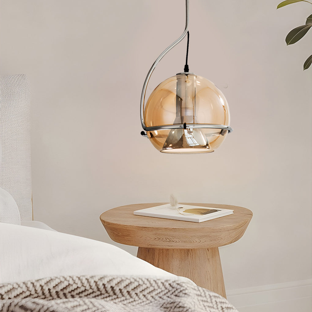 Amber glass globe pendant light above a bedside table, blending warm lighting with natural wood decor.