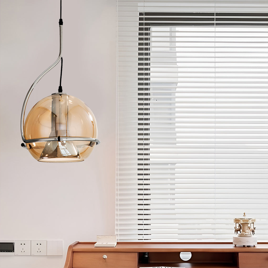 Amber glass globe pendant light hanging near a workspace window, providing focused yet warm illumination.