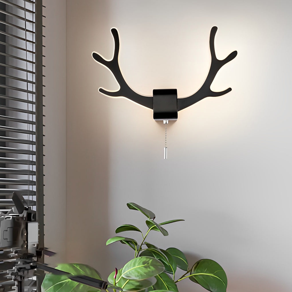 Antler wall sconce light in black finish mounted above indoor plants, creating contrast and artistic wall illumination.