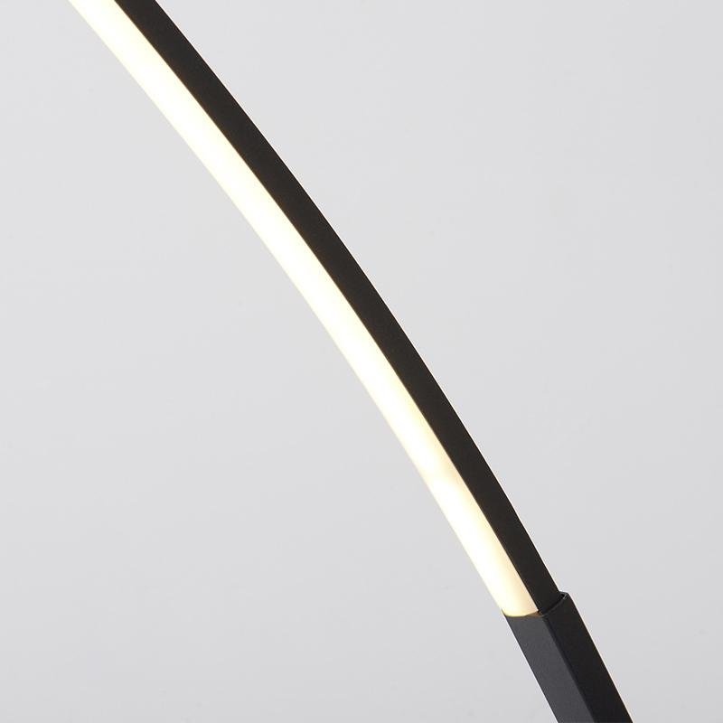 Arcing floor lamp with a minimalist design, providing soft light in a stylish interior.