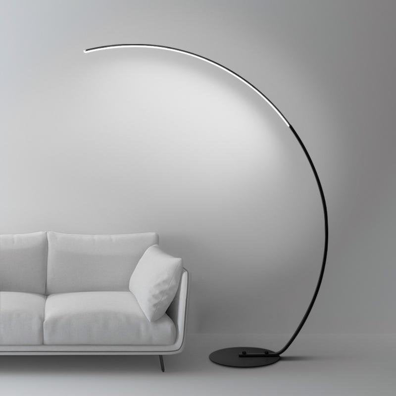 Arcing floor lamp with a sleek design, illuminating a minimalist living room.