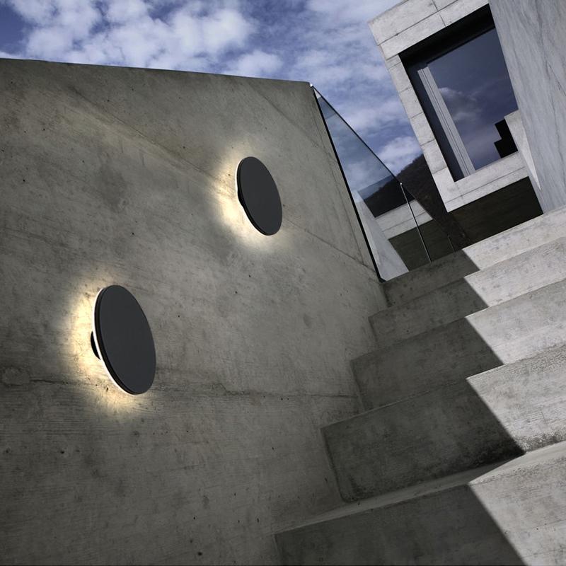 Round backlit wall light mounted on concrete outdoor wall