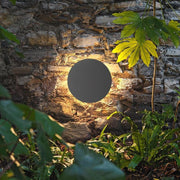Round backlit wall light on stone wall in garden