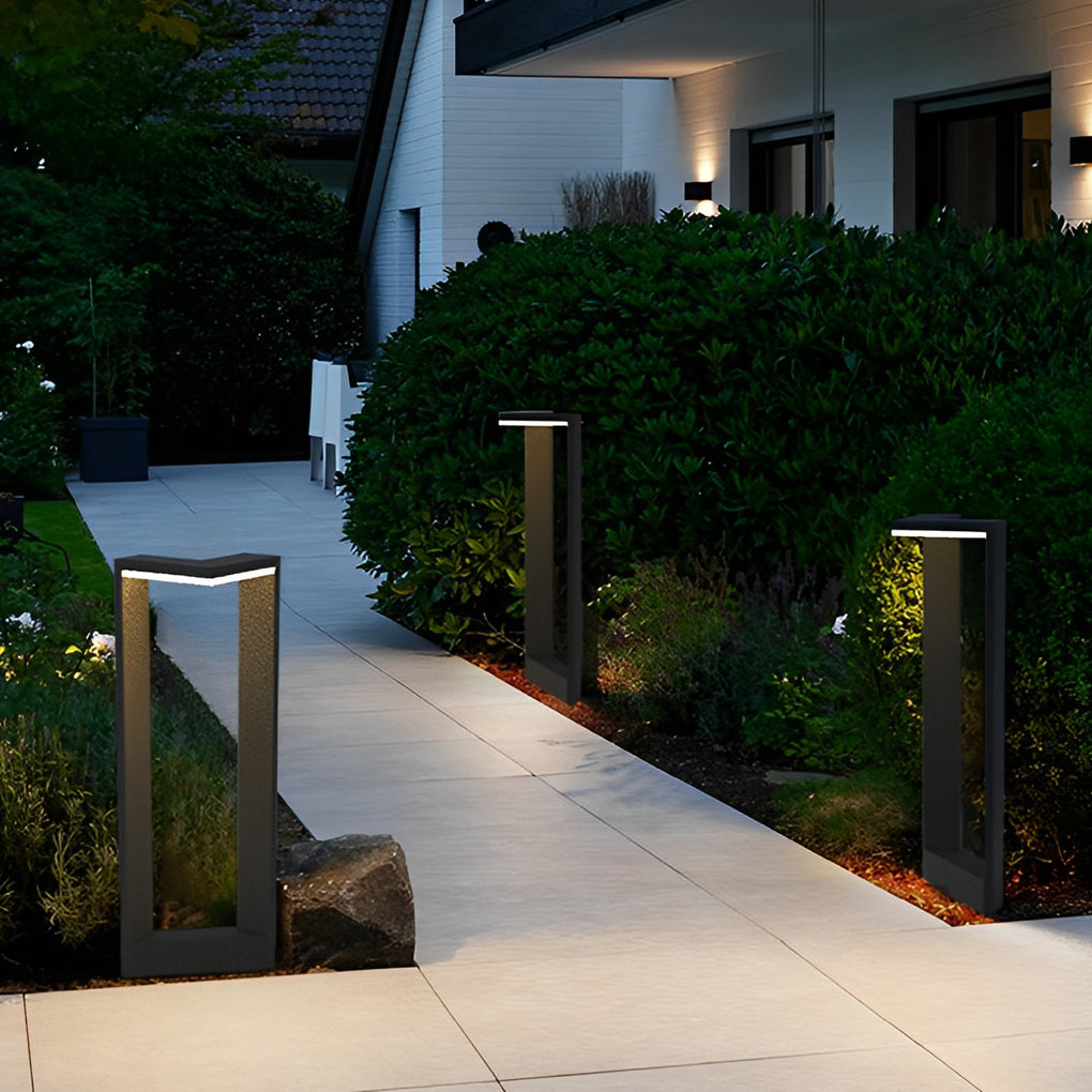 Row of black architectural garden path lights illuminating a modern concrete home walkway ok!!