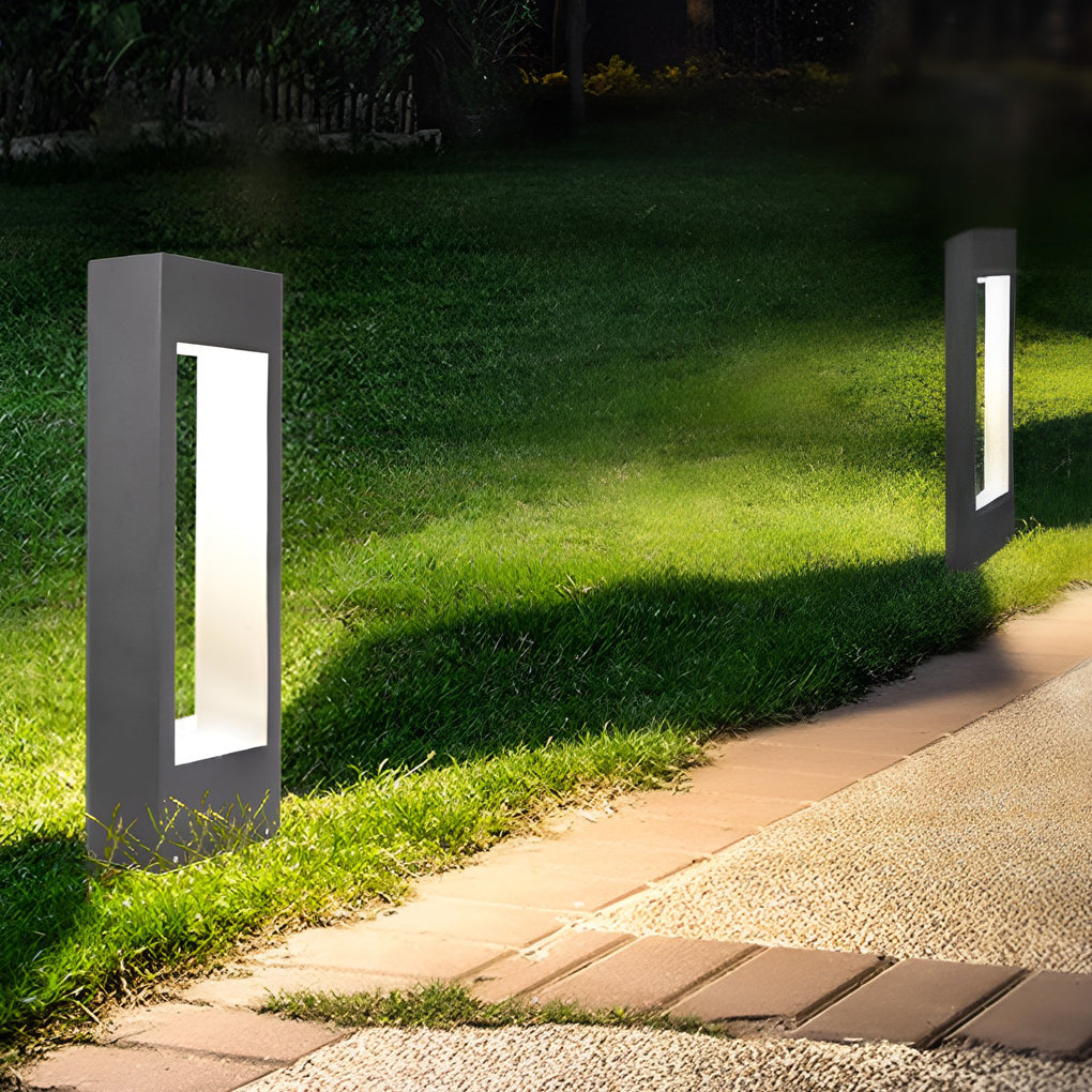 Black bollard lights lining a straight pathway in a landscaped outdoor area at night.