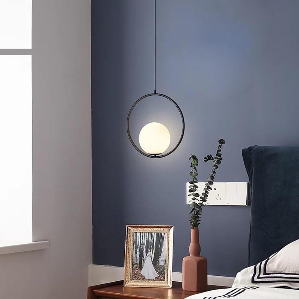 Modern black circular pendant light used as a bedside lamp against a blue bedroom accent wall.
