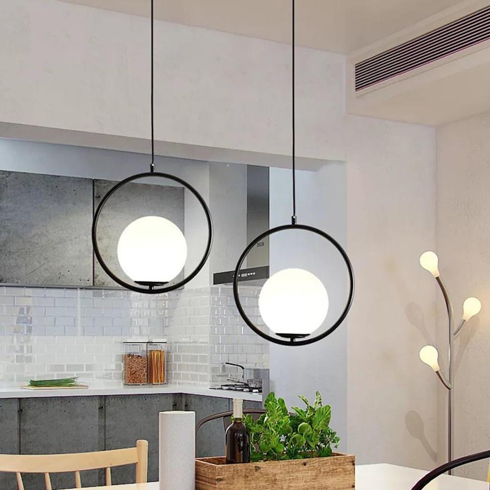Two black circular pendant light fixtures in a modern kitchen and dining area with grey decor.