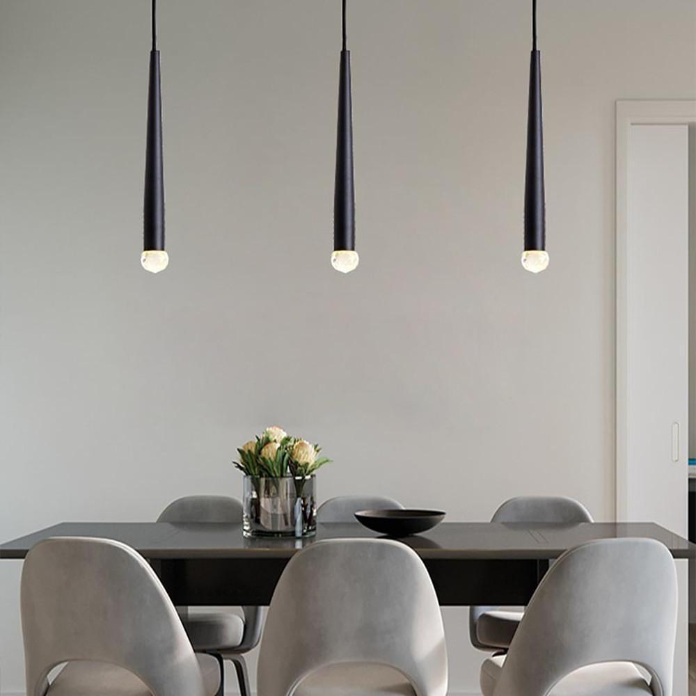 Trio of sleek black cone pendant lights hanging over a dark grey dining table in a minimal room.