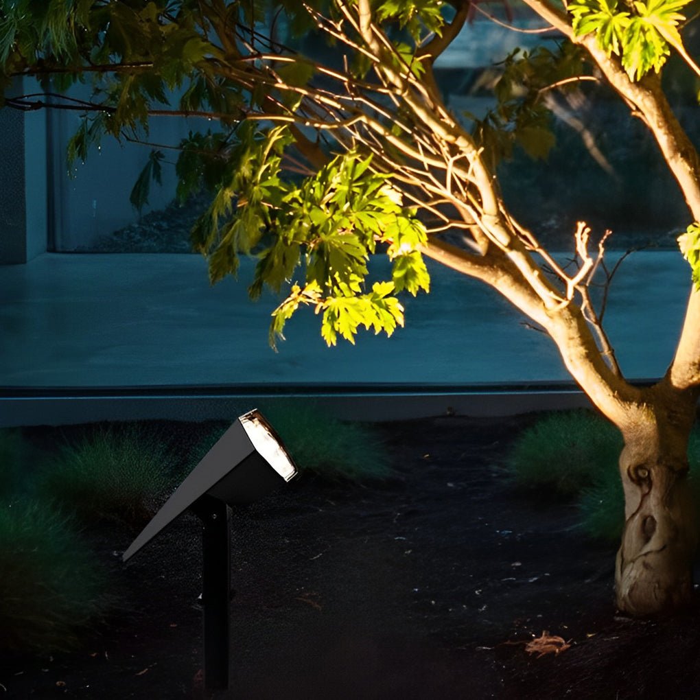 Black flood spike light highlighting tree trunk and foliage with focused beam for dramatic outdoor lighting effect.