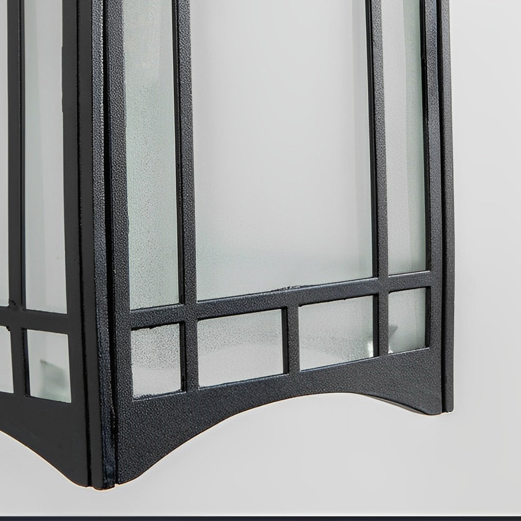 Lantern wall sconce with black frame and frosted glass panels on modern exterior wall.