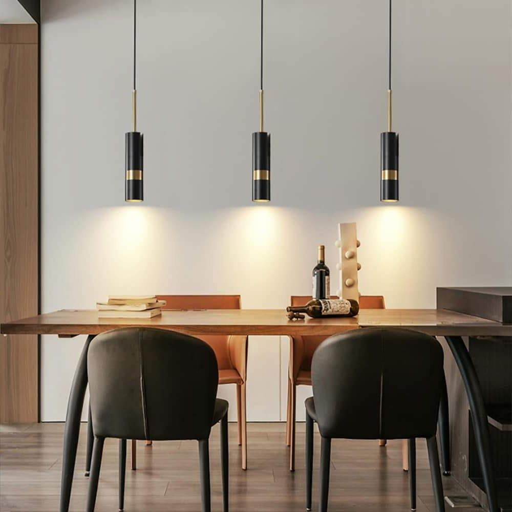 Three black adjustable cylindrical pendant lights hanging over a modern dining room set table.