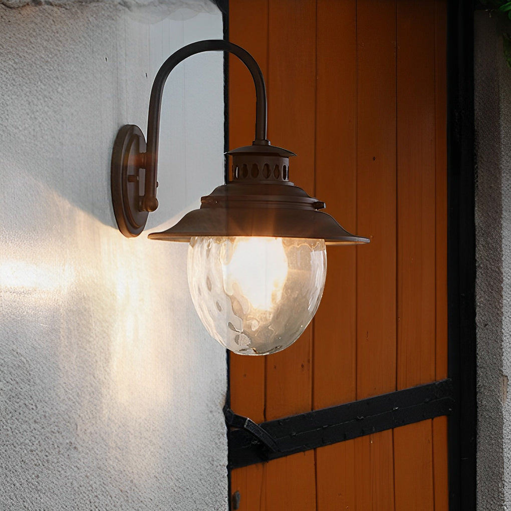 Black gooseneck wall light illuminating rustic wooden door entrance, vintage outdoor fixture providing warm welcoming glow.