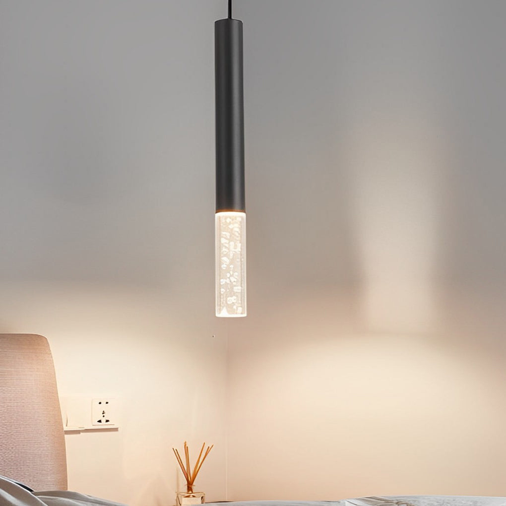 Single Black LED Cylinder Pendant light featuring seeded bubble glass over a modern nightstand.