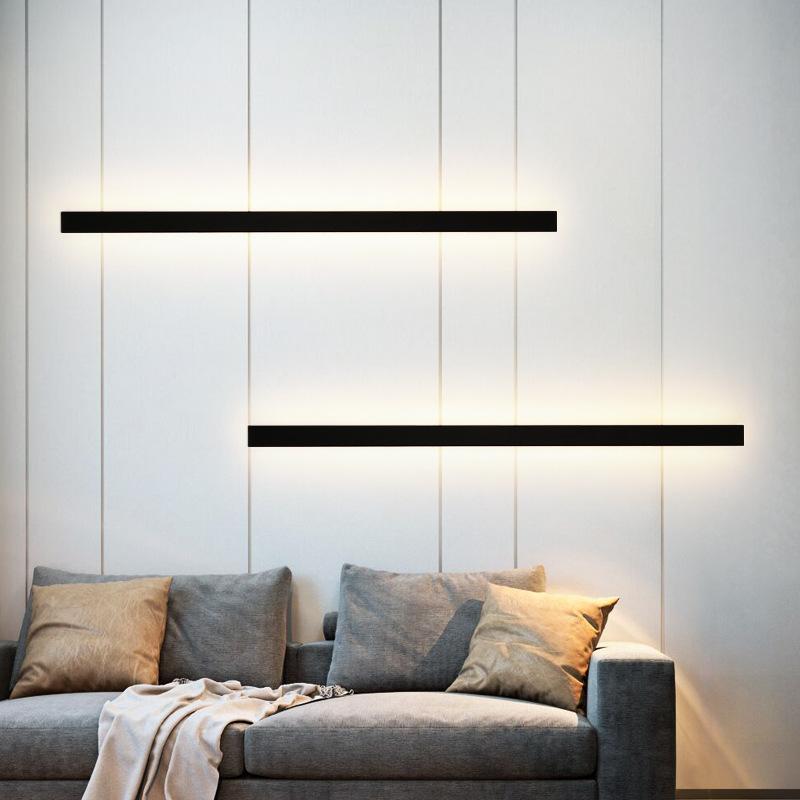 Black linear wall sconce enhancing a cozy living room with modern vertical lighting.