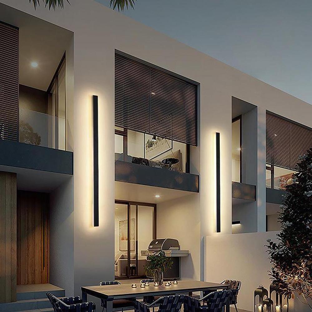 Black linear wall sconce providing elegant light along a modern outdoor corridor.
