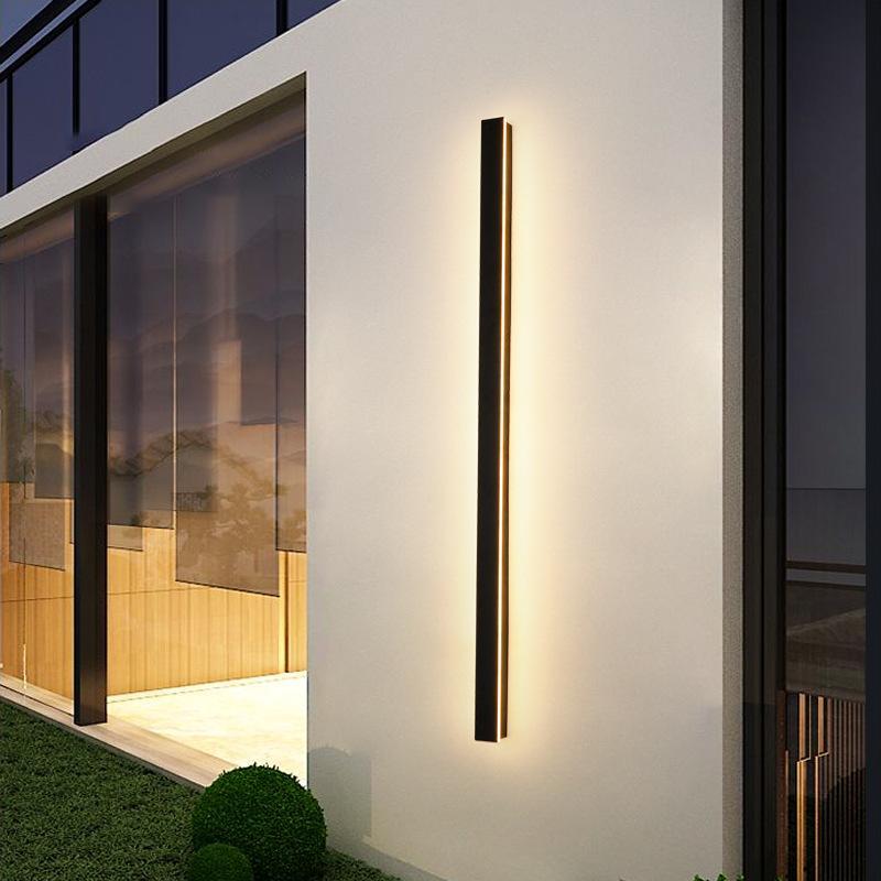Black linear wall sconce illuminating a stylish patio with soft linear light.