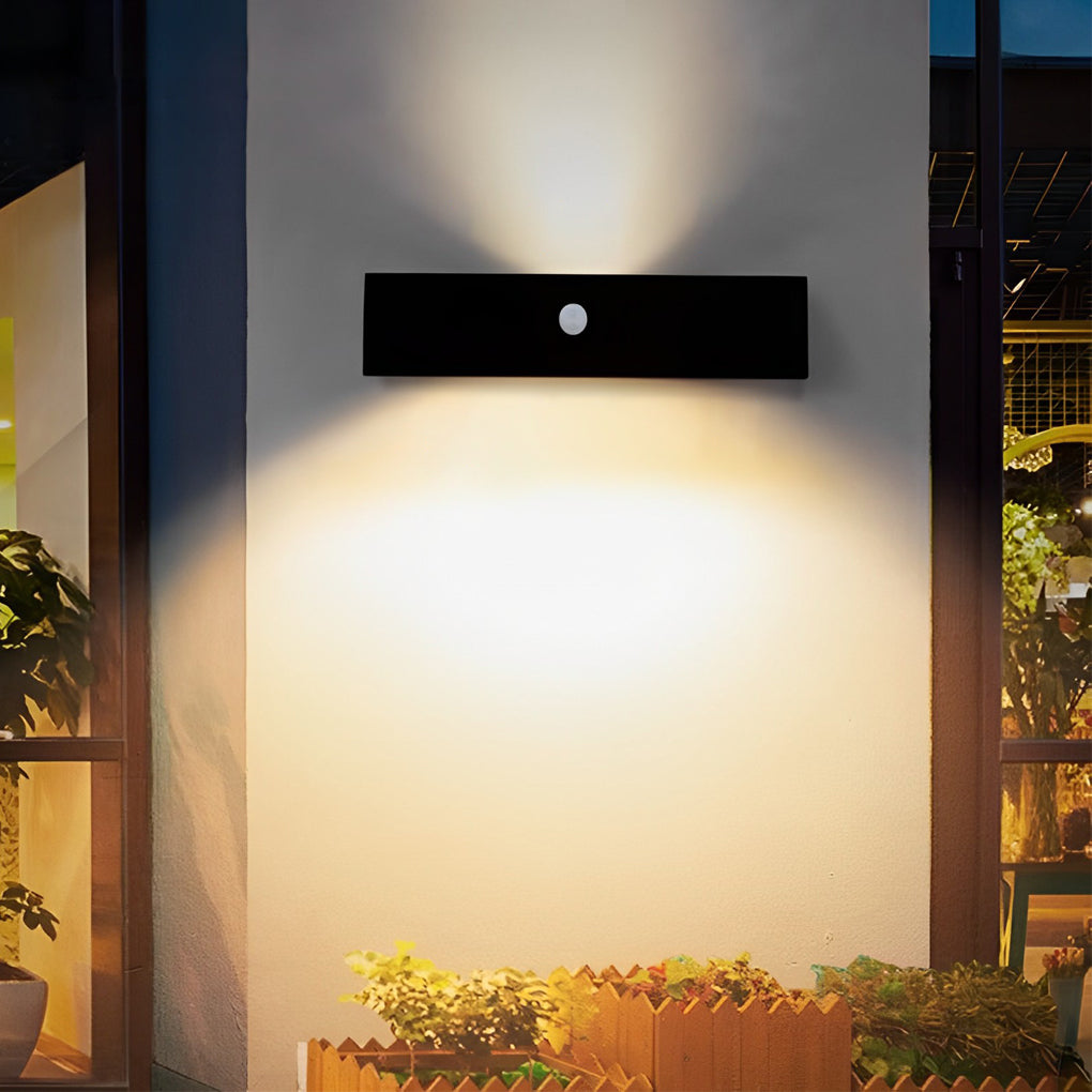 Black motion sensor outdoor wall light illuminating a minimalist exterior wall with focused glow.