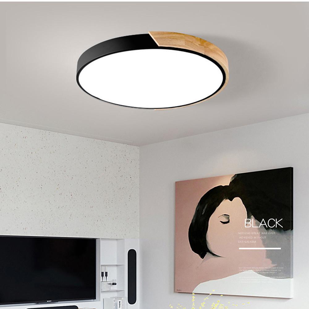 The black nordic wooden ceiling light glowing above a television and portrait artwork here ok.