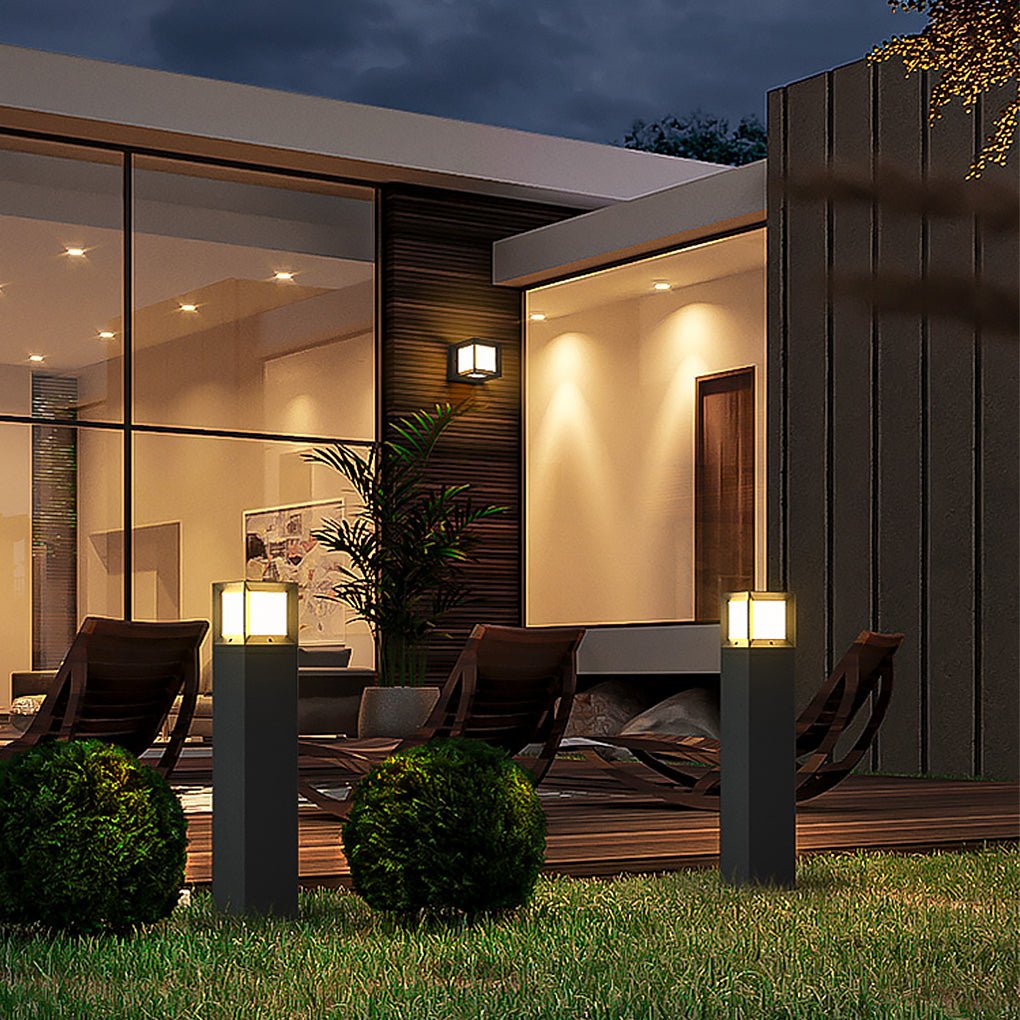 Black outdoor bollard lights illuminating a beautiful modern backyard patio with lounge chairs.