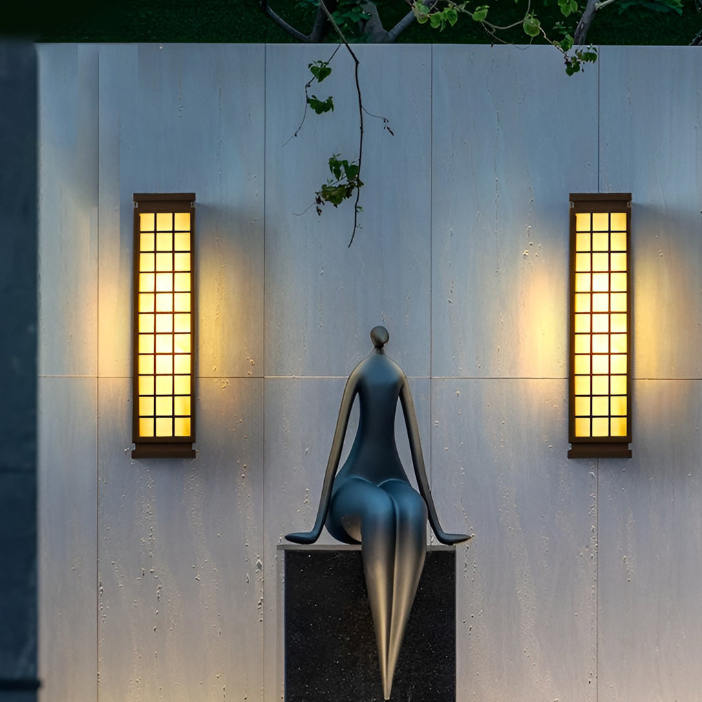 Black outdoor sconce light featuring grid pattern and warm lighting beside vertical wooden slats.