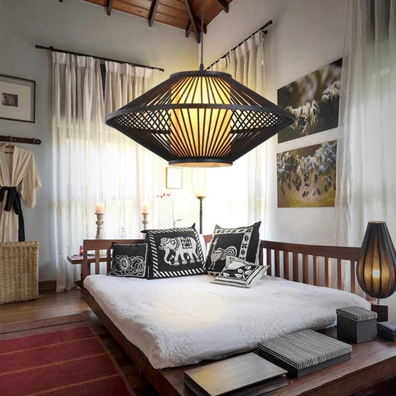 Black rattan pendant light with a geometric design, mounted above a modern bed.