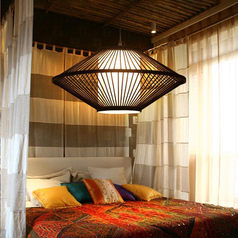 Black rattan pendant light with a geometric design, providing warm illumination in a cozy bedroom.