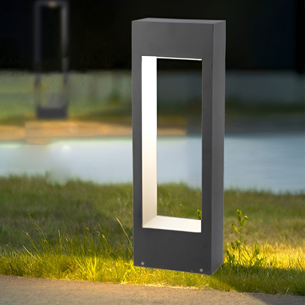 Black rectangular bollard light illuminating lawn grass with downward lighting effect.
