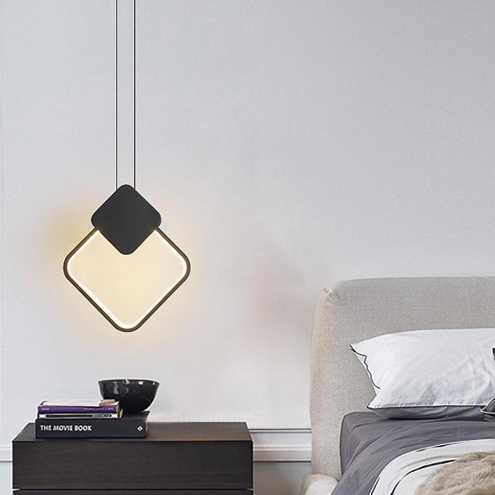Black square geometric pendant light suspended above nightstand.