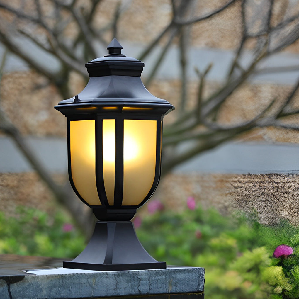 Classic black vintage outdoor pillar lantern with warm frosted glass glowing on a stone wall.