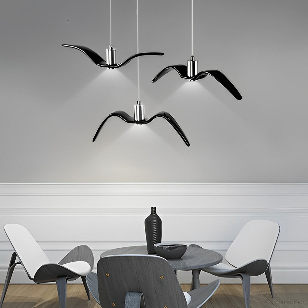 Black wing pendant lights over a round dining table in a minimalist room.