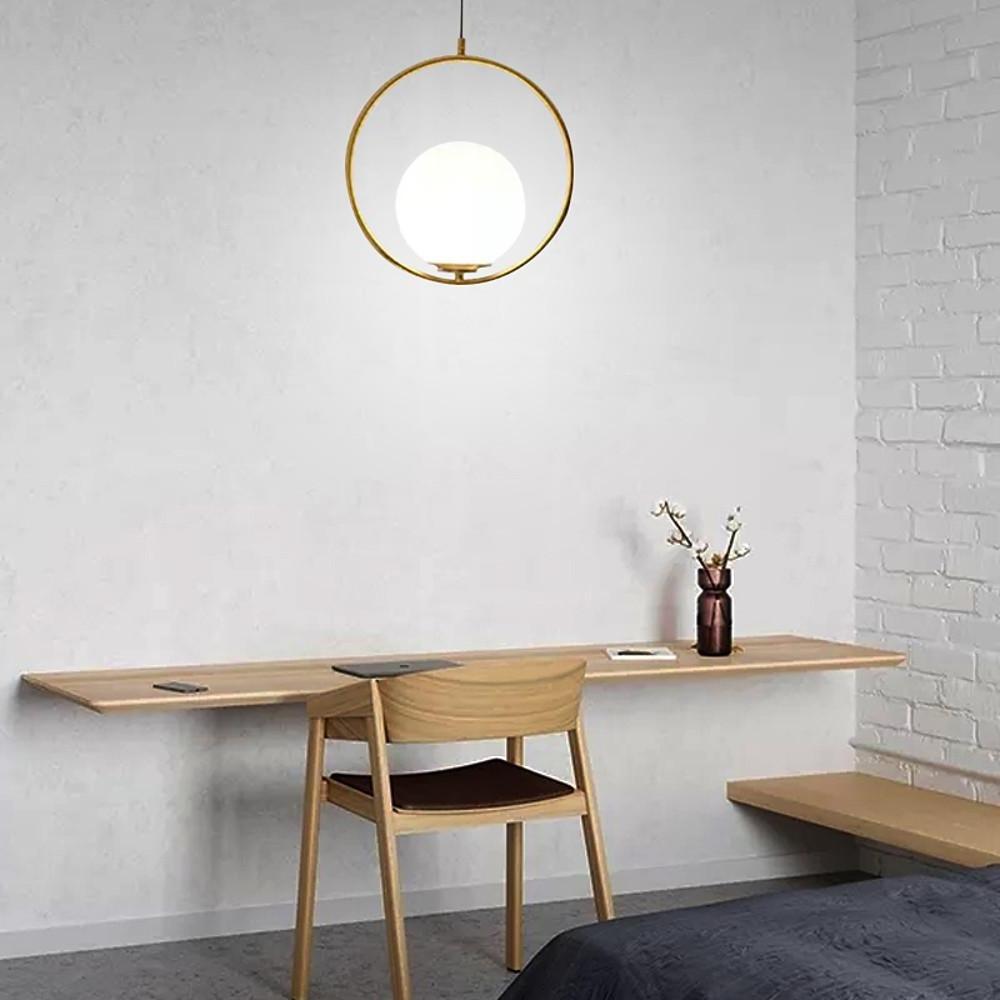 Modern minimalist hanging lamp with a brass circle design above a floating wood office desk.