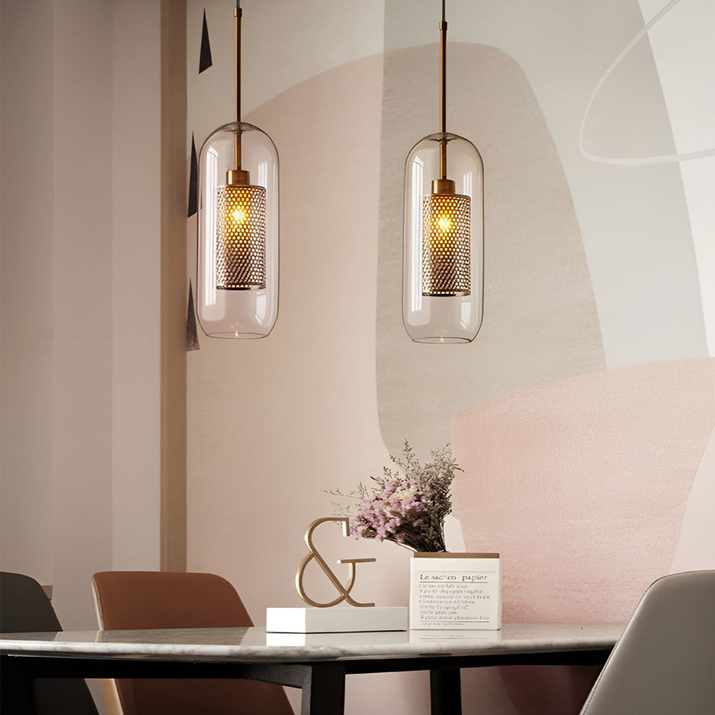Pair of capsule Clear Glass Globe Pendant variants with gold mesh above a chic dining table.