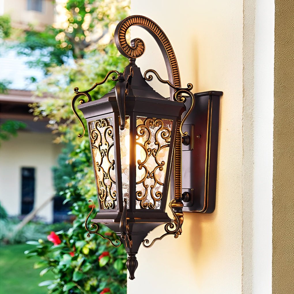 Classic antique outdoor wall sconce installed on garden-facing wall with intricate metal frame and glass panels.