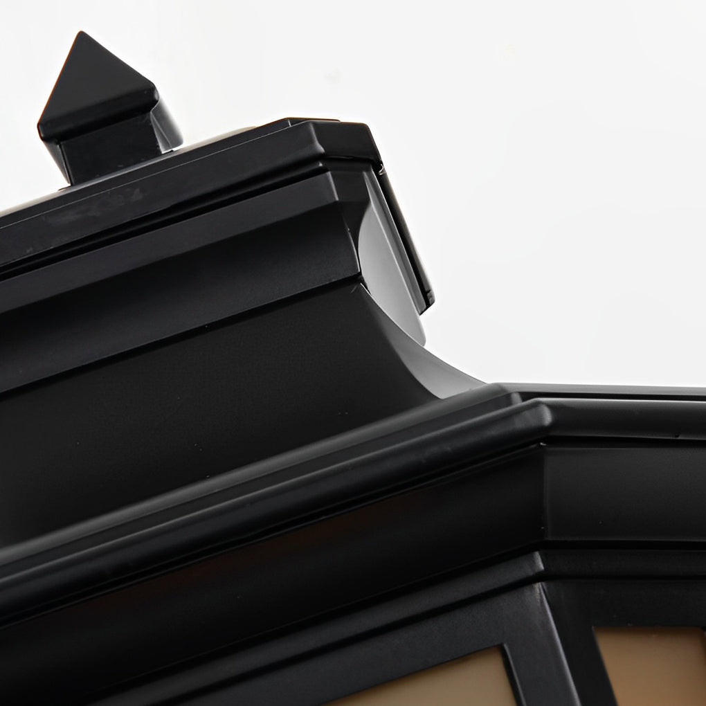 Close-up of the black metal top cap on a vintage outdoor pillar lantern with a finial detail.