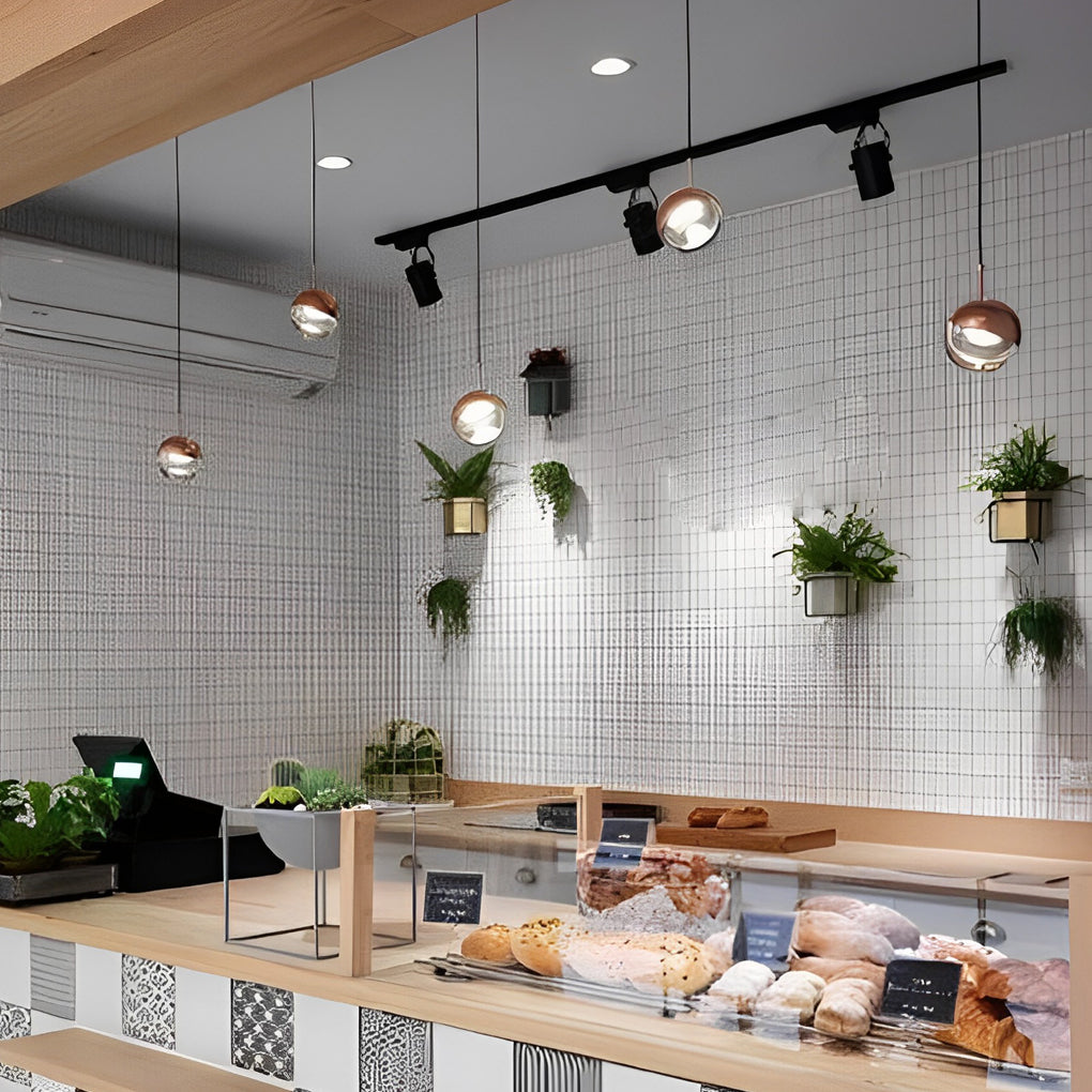 Row of globe pendant light fixtures in a modern bakery shop over a fresh bread display case.