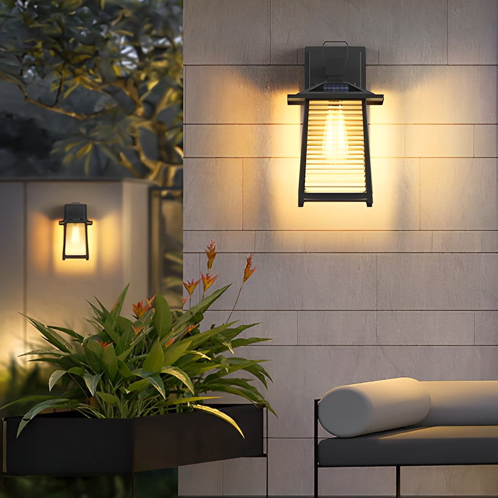 Contemporary lantern outdoor wall light casting a soft glow on a modern home's exterior wall.