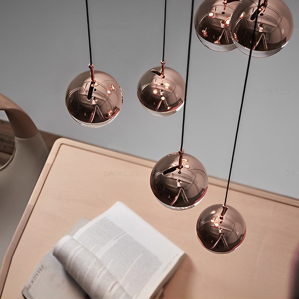Close up of copper globe pendant light spheres casting light on a desk with an open book page.