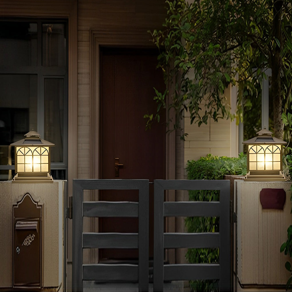 Copper pillar lights casting a gentle glow near a wooden fence.