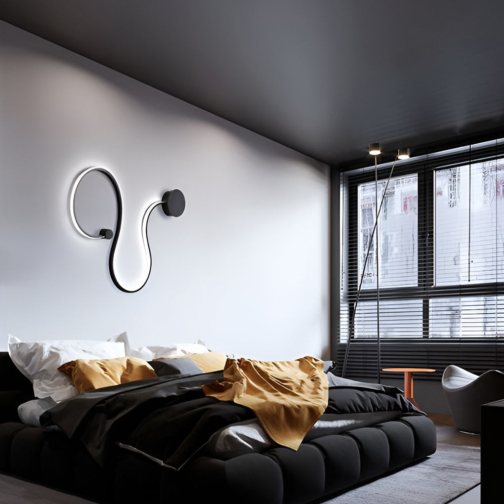Modern curved wall sconce illuminating a bedroom wall with indirect light.