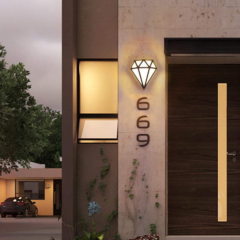 Diamond shape wall light with a black finish, illuminating a modern outdoor space.