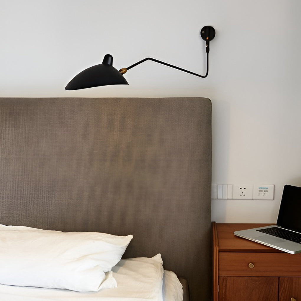 Double arm wall sconce mounted beside a bed, combining compact design with flexible task lighting.