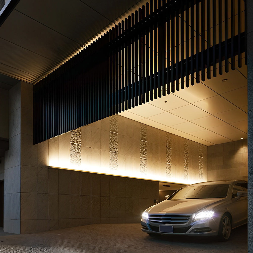 Driveway and building entrance illuminated by exterior facade wall washer lights.