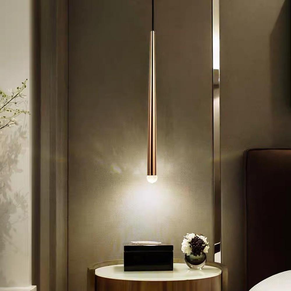 Elegant Slim Gold Cone Pendant with a glowing crystal orb over a side table in a warm modern room.