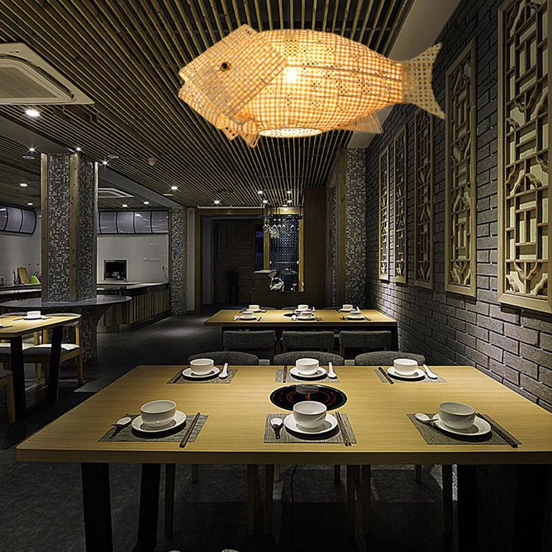 Fish pendant light with a rattan finish, hanging in a modern restaurant interior.
