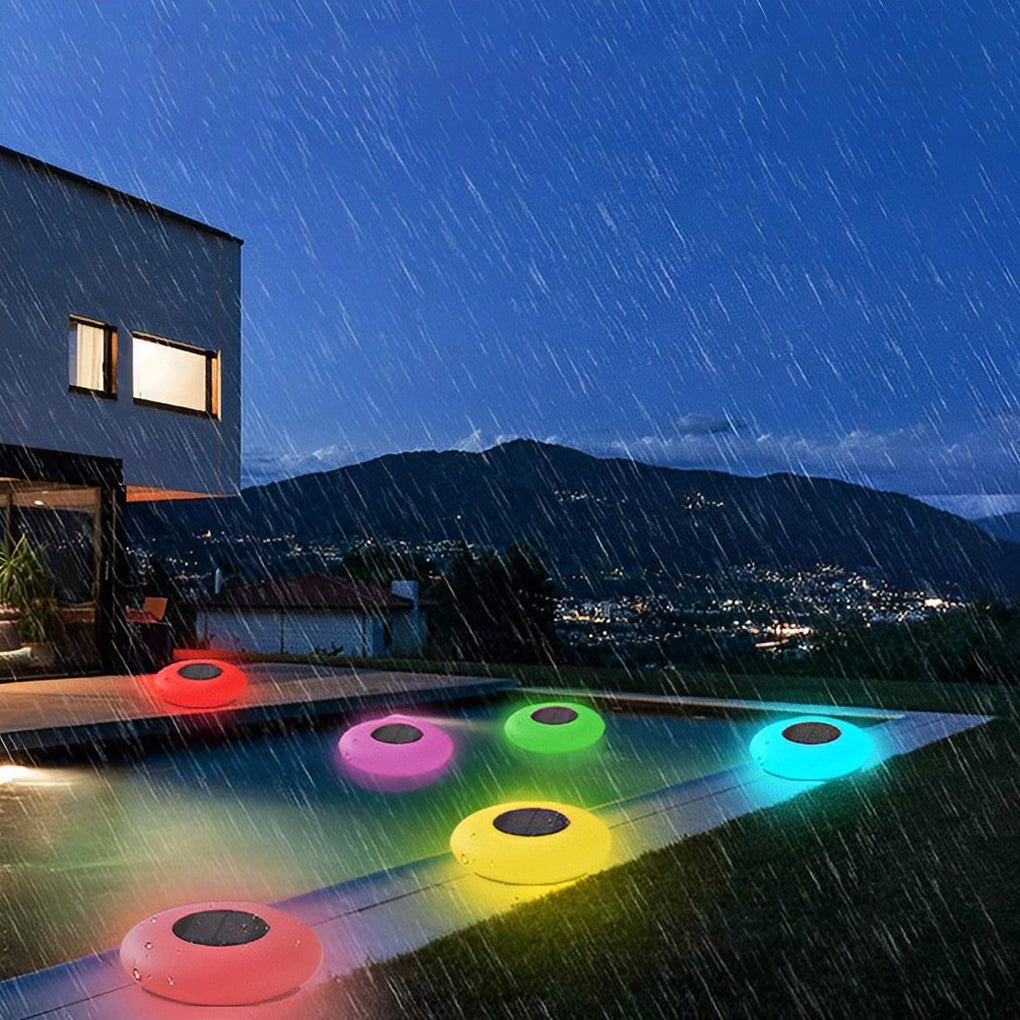 Floating pond lamps glowing beside pool on rainy night