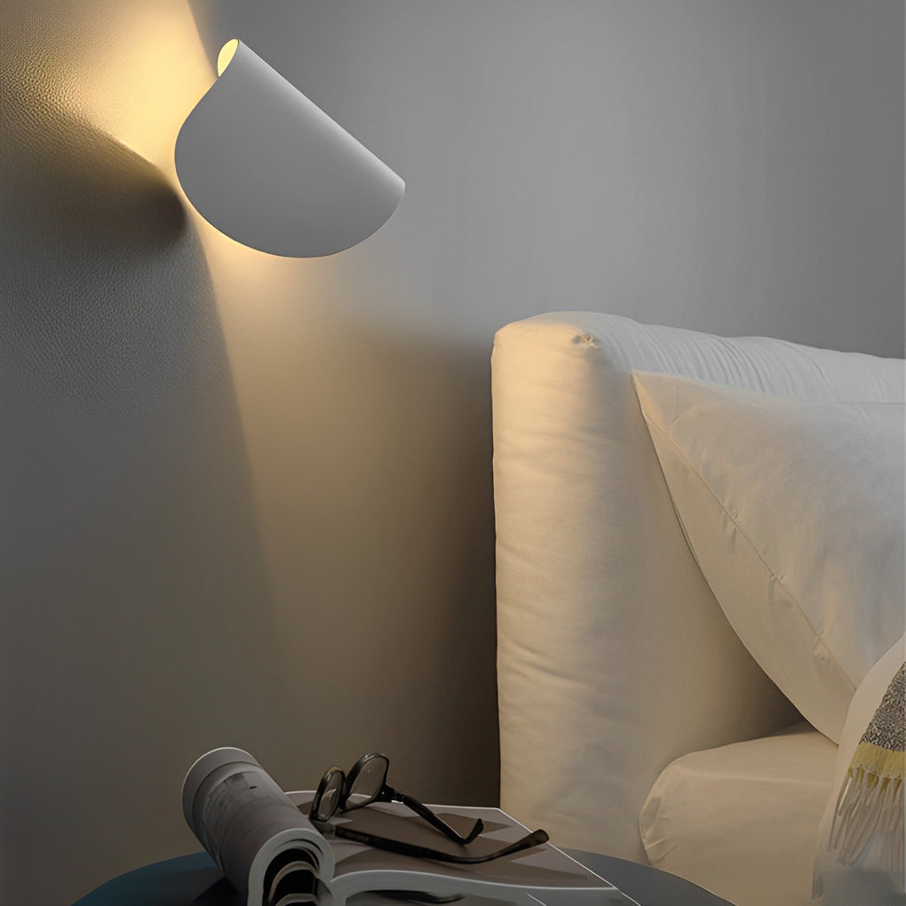 Folding wall sconce providing soft illumination in a stylish bedroom.