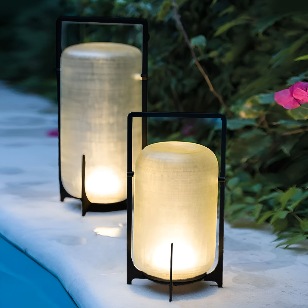 Outdoor modern handle lantern with frosted glass shade on wooden deck beside ottoman.