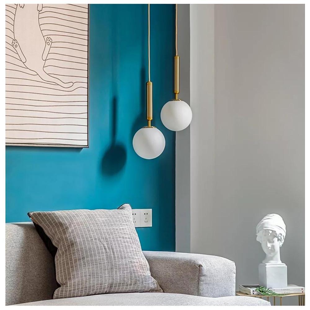 Pair of frosted globe pendant light fixtures illuminating a stylish living room with blue walls.